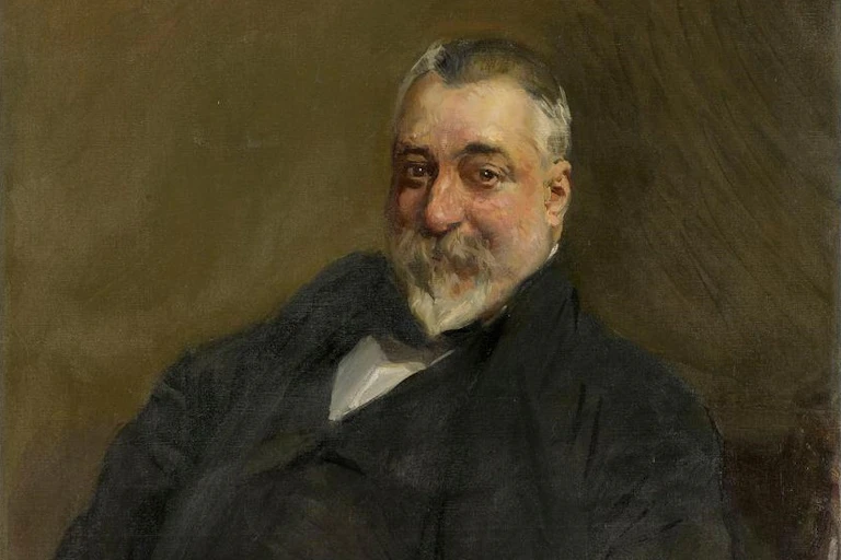 Retrato de un hombre sentado con barba blanca.