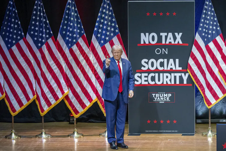 Donald Trump standing on stage next to a sign reading: 'no tax on social security'.