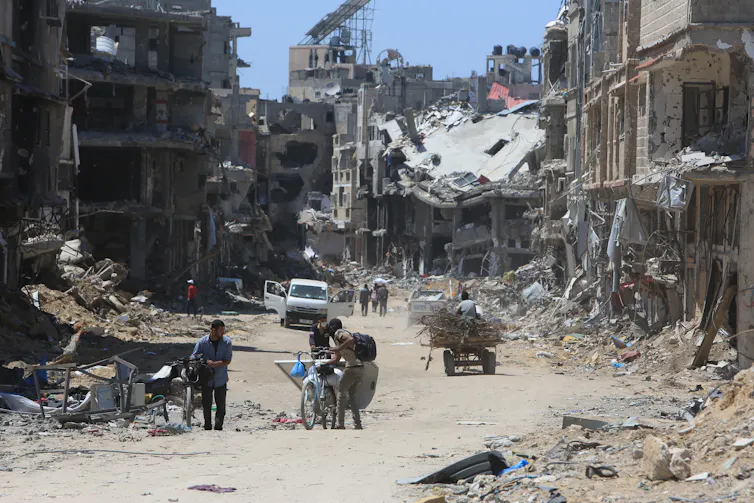Des Palestiniens marchent dans une rue de Gaza détruite lors des affrontements