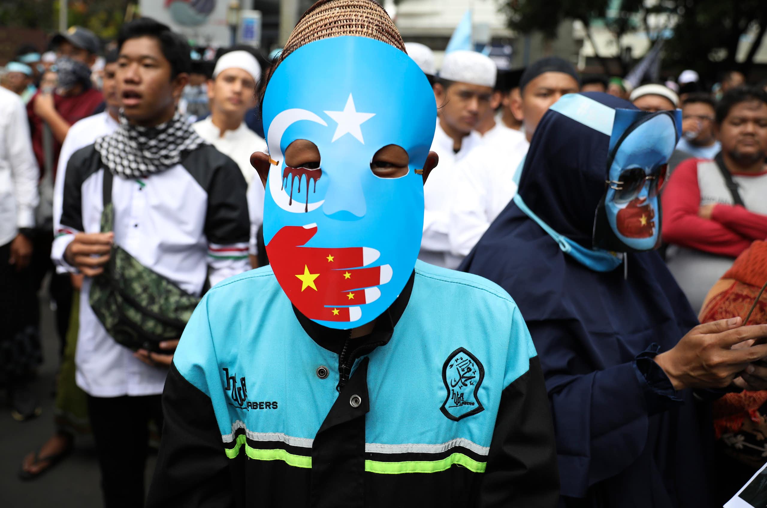 A protestor in a blue mask with a red hand over the mouth.