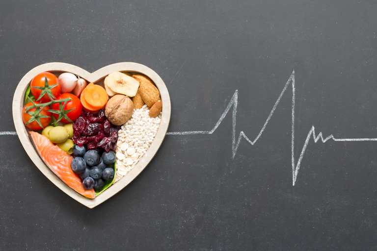 Um prato de alimentos saudáveis em forma de coração contra um quadro negro com um contorno de giz de uma leitura de eletrocardiograma