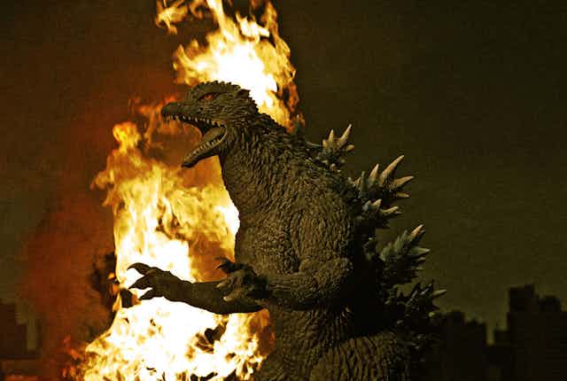 Godzilla with a burning city behind him