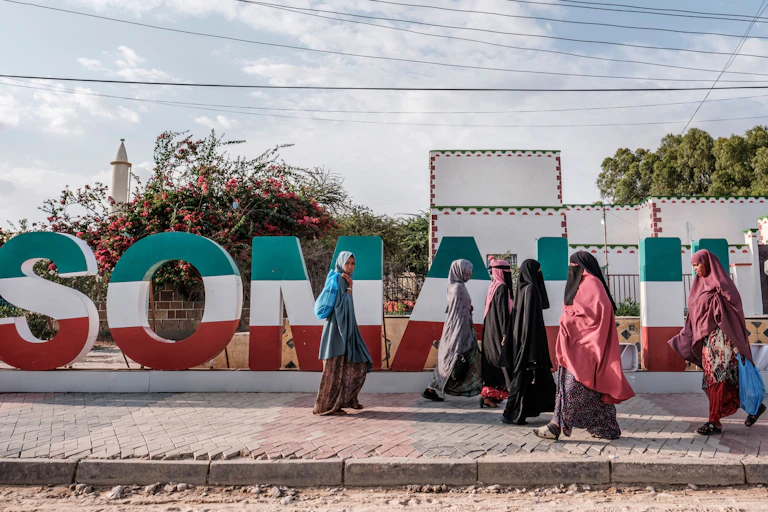 Women walking in front of Somaliland lettering in green, white and red