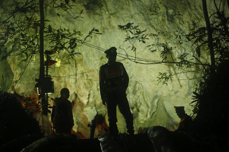 Silhouette of a man in an army uniform standing in front of a cave