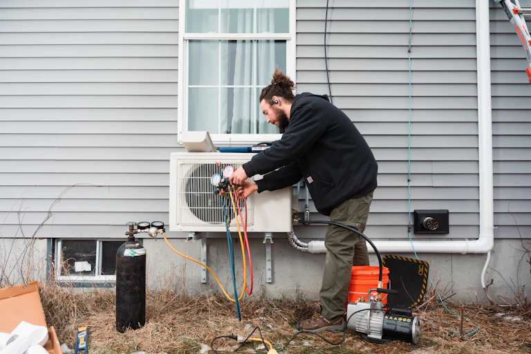 A man installs in a heat pump on an older house.