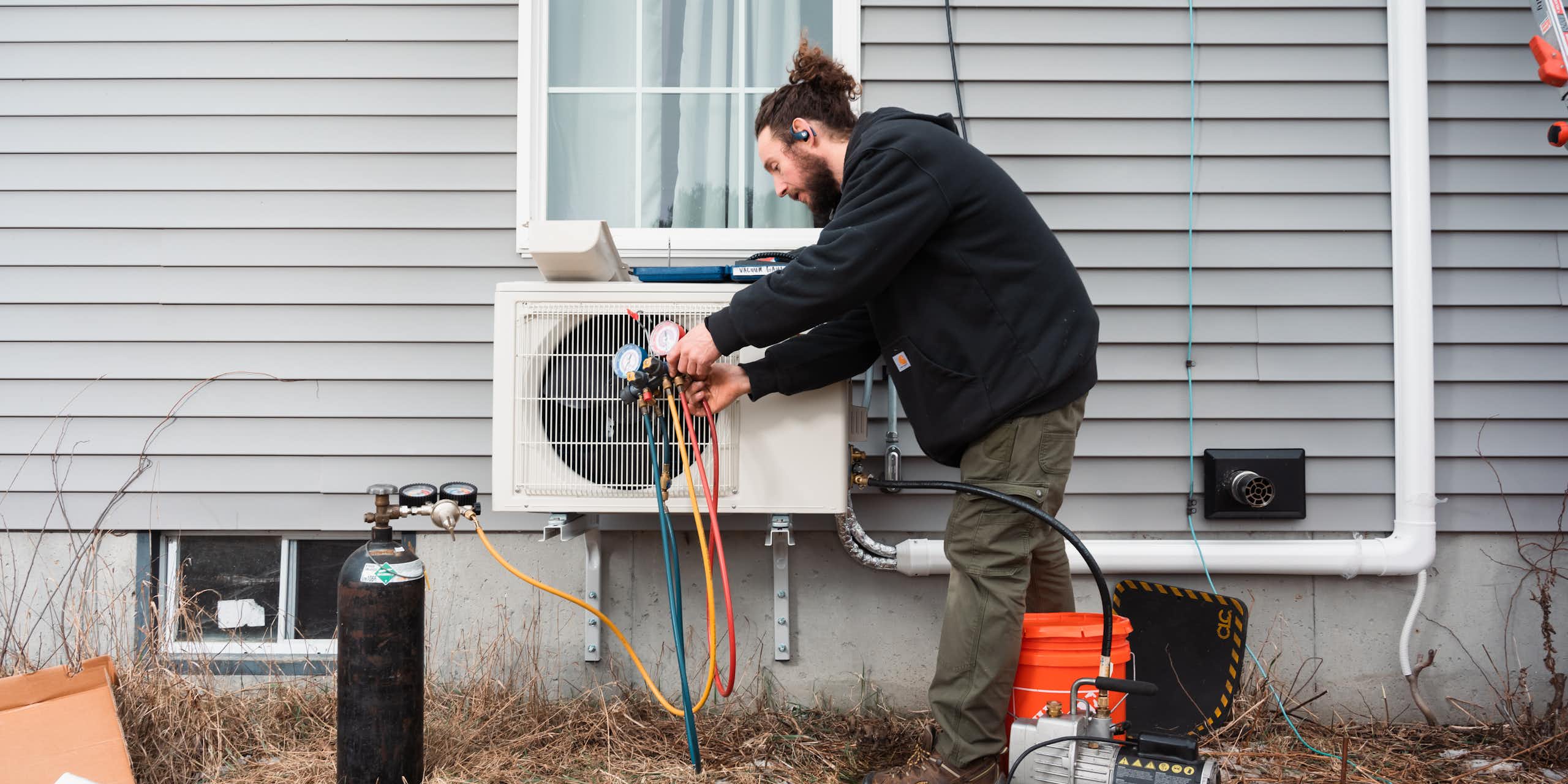 A man installs in a heat pump on an older house.
