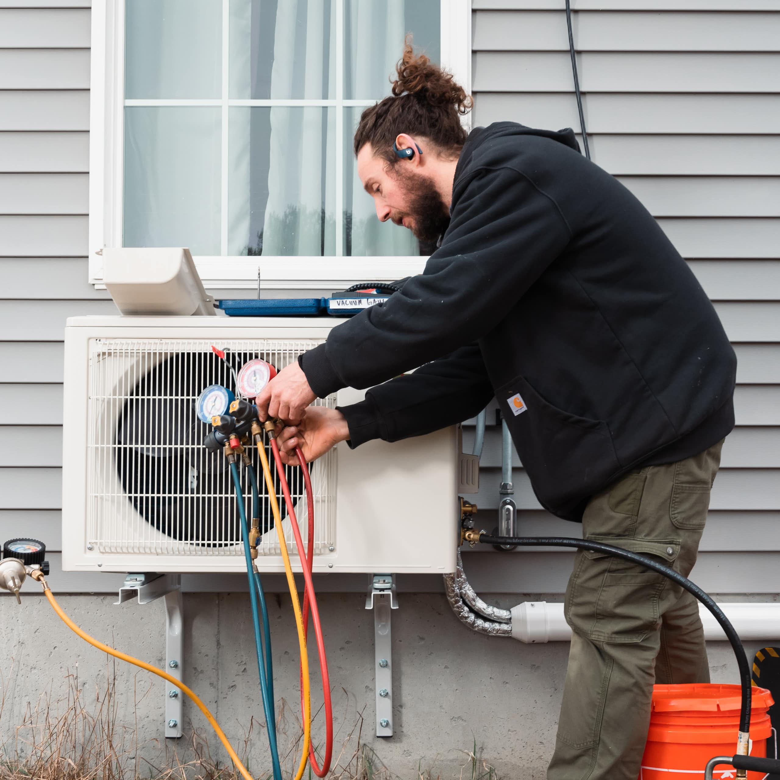 A man installs in a heat pump on an older house.
