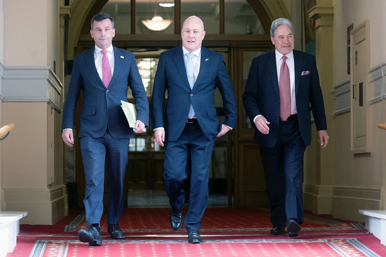 Three men in blue suits walk along a corridor