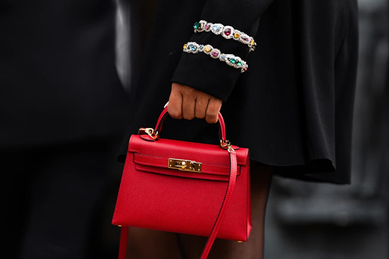 A woman holds a red luxury handbag