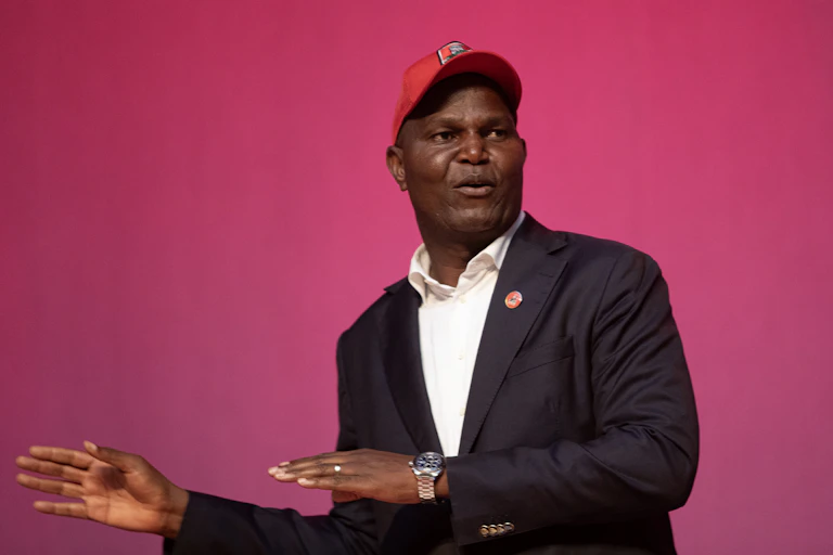 A man wearing a cap speaks to an audience.