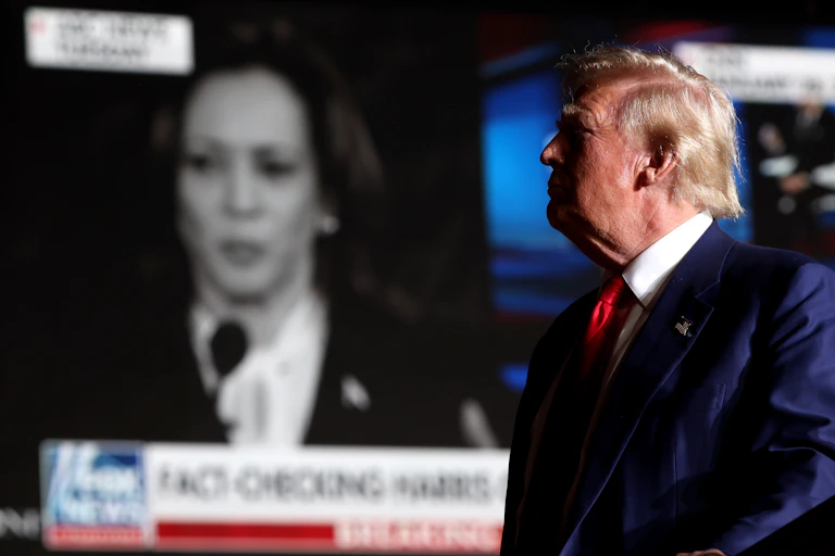 Donald Trump watches Kamala Harris on TV.