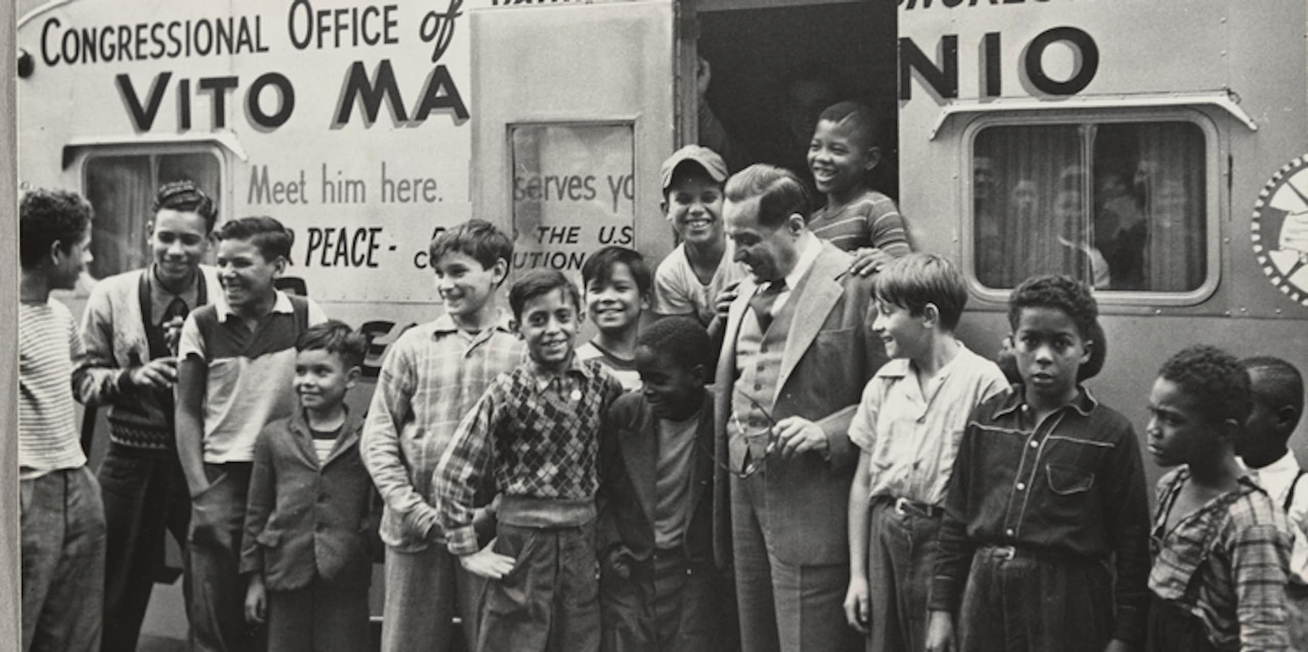 Marcantonio is surrounded by young men in front of his office.