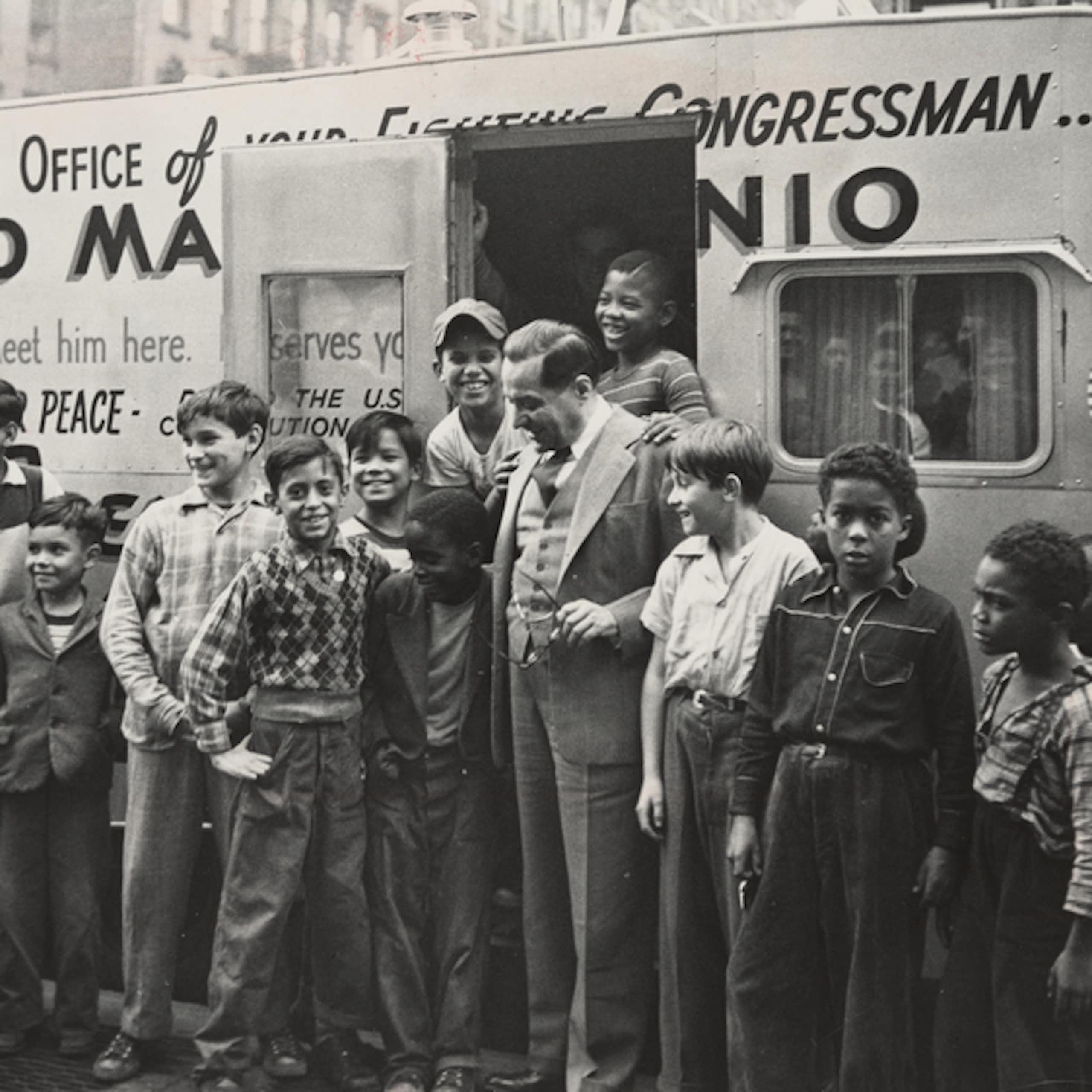 Marcantonio is surrounded by young men in front of his office.