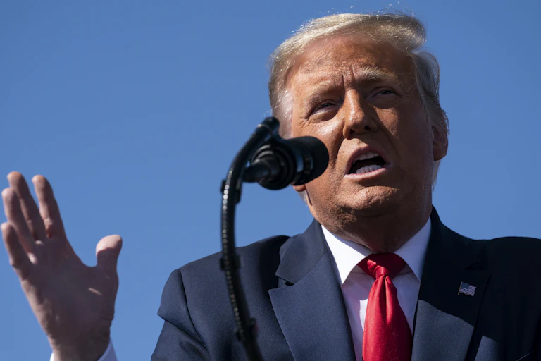 Donald Trump speaks outdoors in front of a microphone.