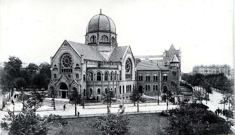 A black and white photo of an ornate building with a central dome several stories high.