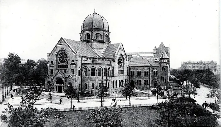 A black and white photo of an ornate building with a central dome several stories high.
