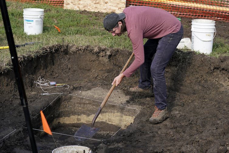 A man seems to look intently as he digs with a shovel.