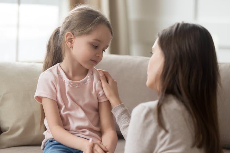 A young girl being comforted by an adult woman.