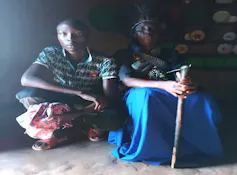 Two people, one holding a walking stick, look directly at the camera