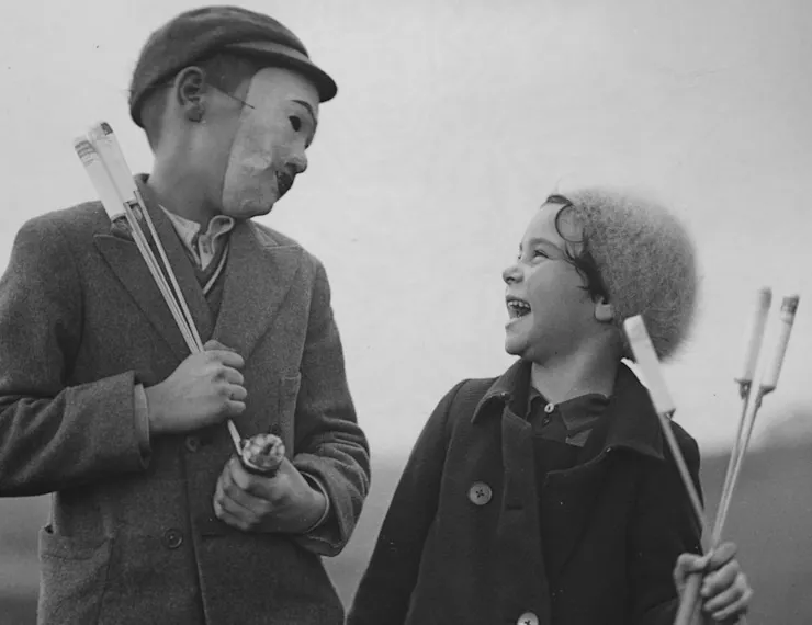 Black and white photo of a masked boy and girl holding fireworks.