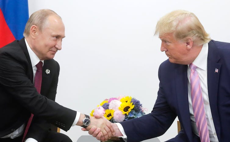 Two men wearing suit shake hands