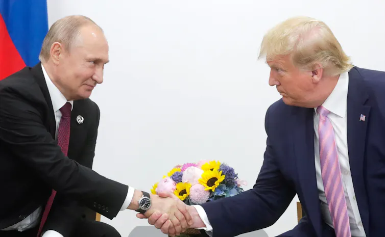 Two men wearing suit shake hands