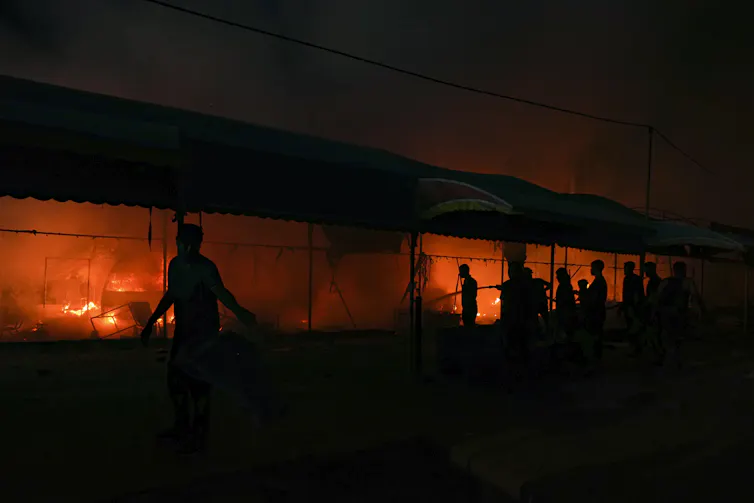 People carry pails during a night-time fire.