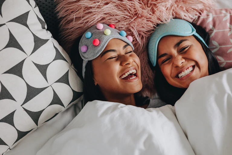 Two young women wearing eye masks and smiling