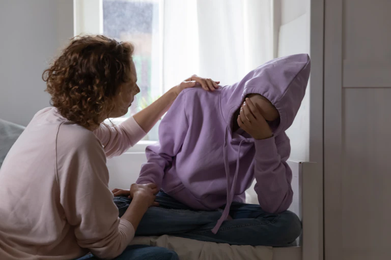 Woman comforts child wearing hoodie