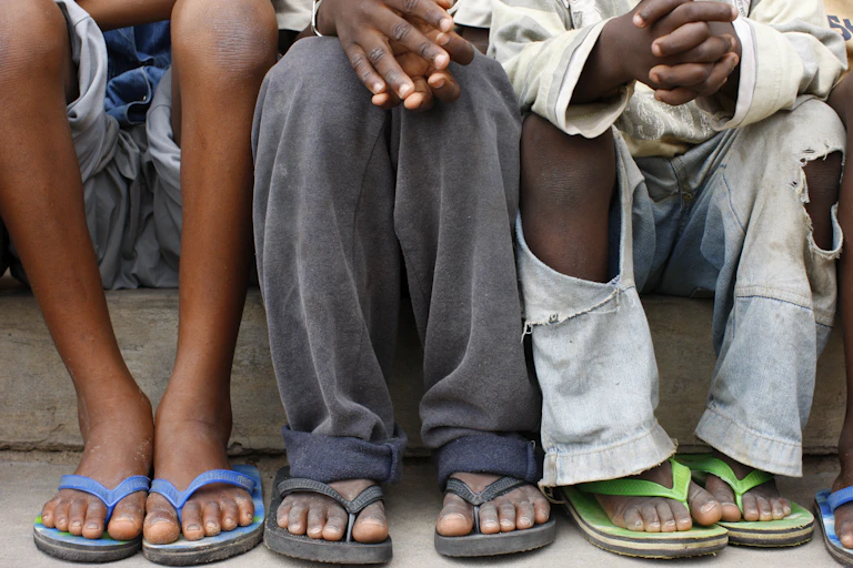 The legs and sandaled feet of three children