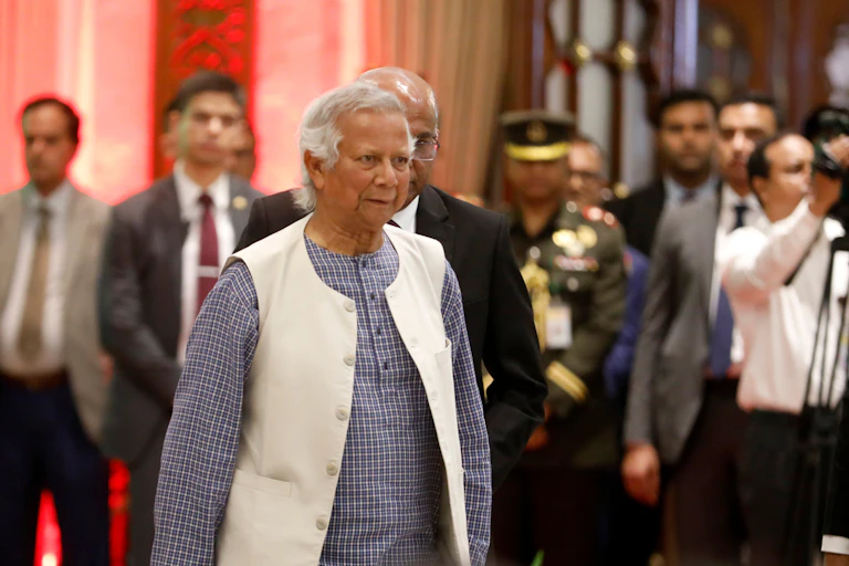 M. Yunus habillé avec une chemise grise quadrillée blanche avec un long gilet blanc