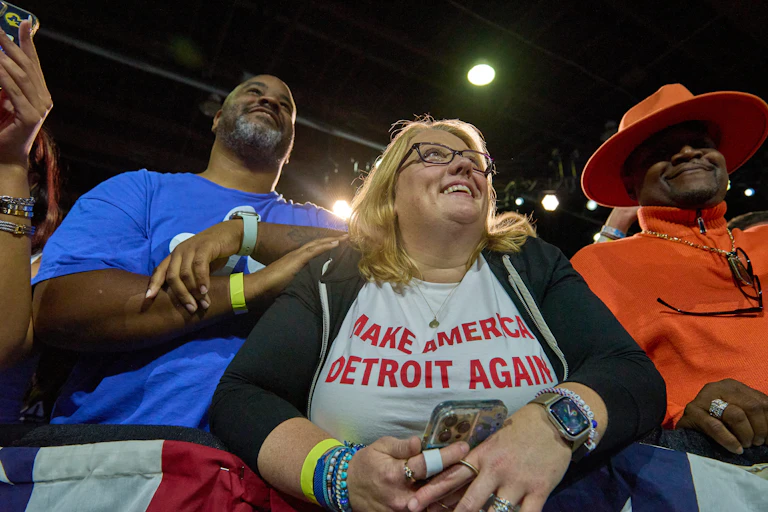 A smiling woman wears a T-shirt reading "Make America Detroit Again"