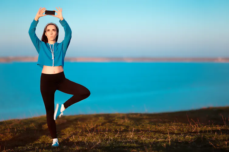 Woman taking a selfie while doing a yoga pose.