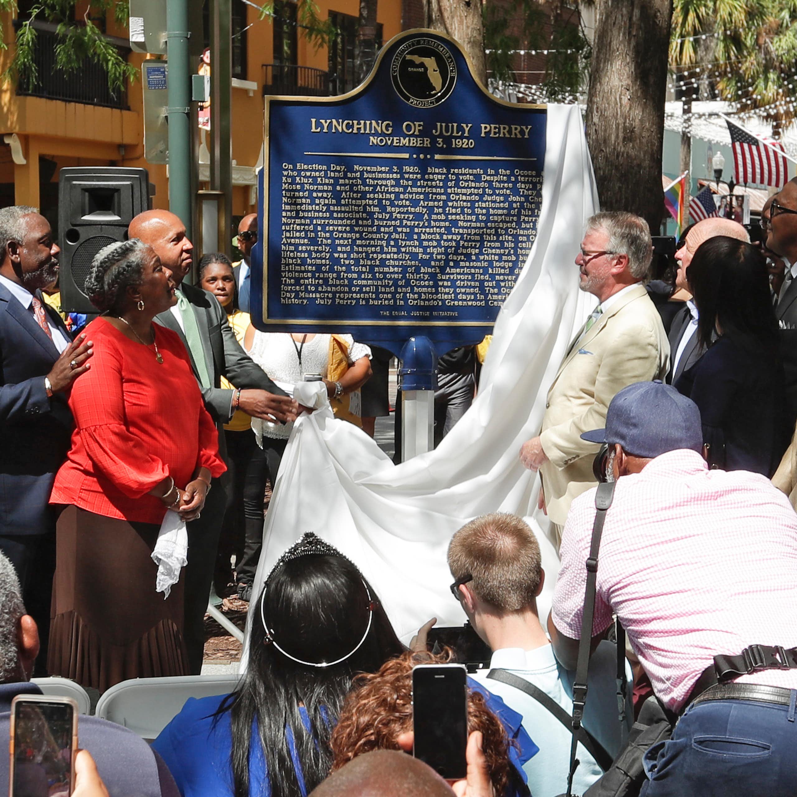 A group of Black people watch the unveiling of plaque that details the lynching of a Black man.