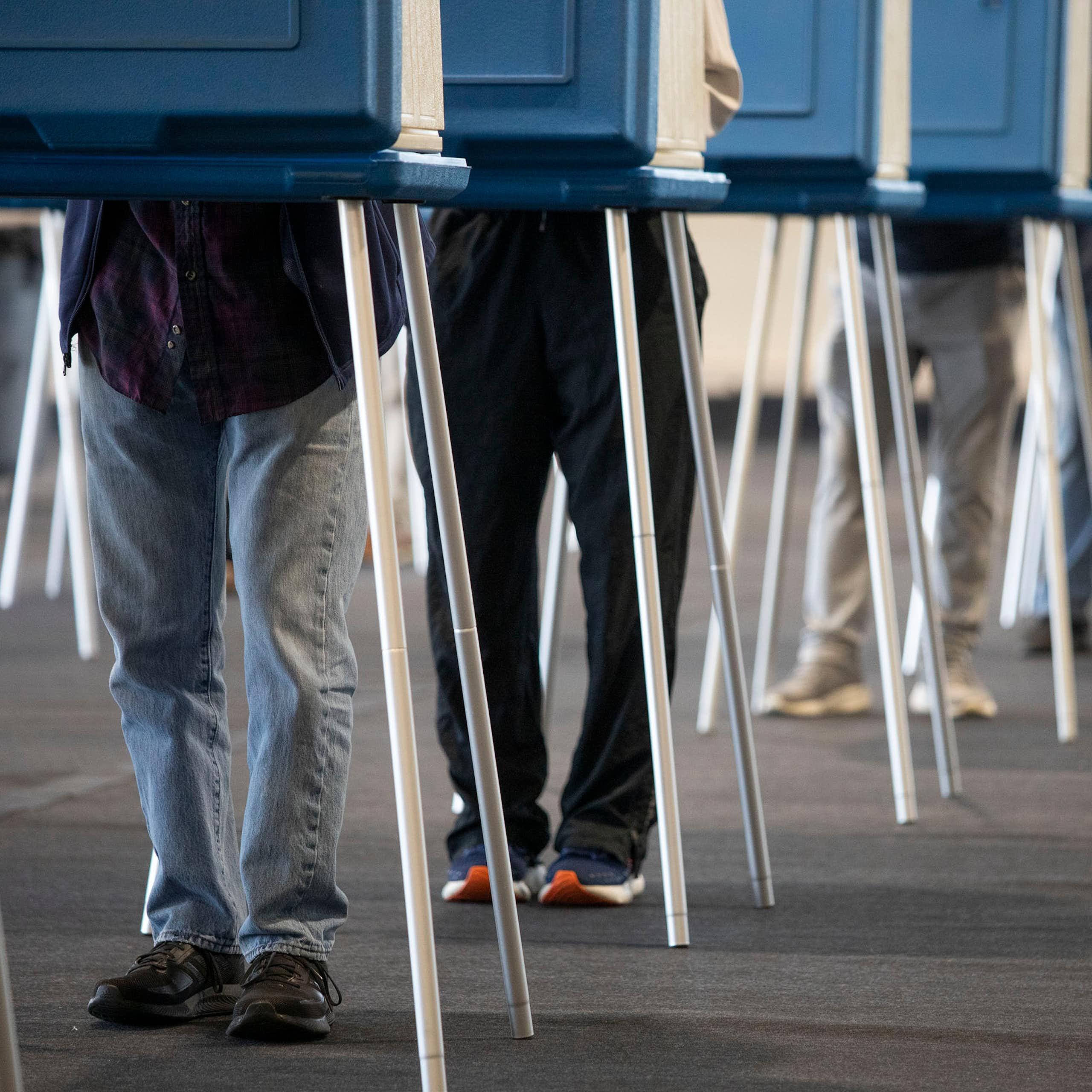 A row of people's legs are seen at blue booths.