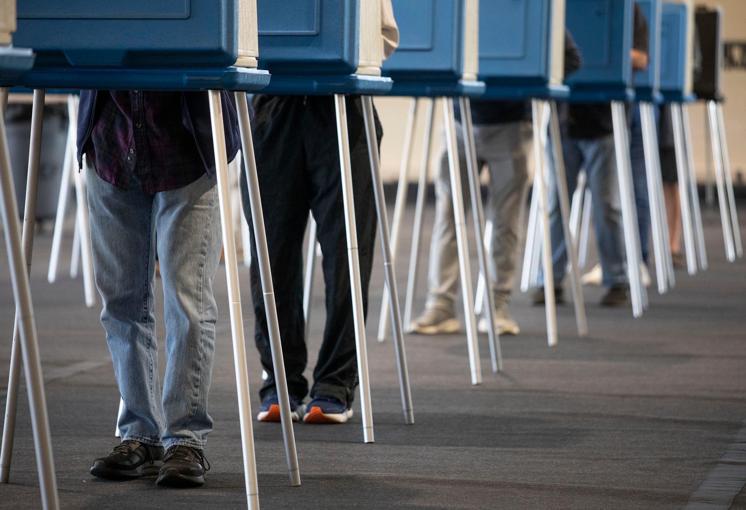 A row of people's legs are seen at blue booths.