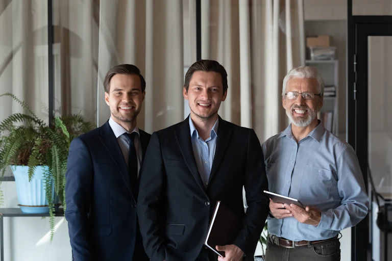 trois hommes de génération différente souriants et habillés de façon classique