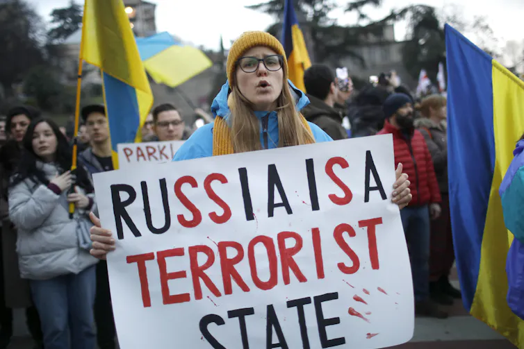 A young Georgian woman holds up a sign reading 'Russia is a terrorist state'.