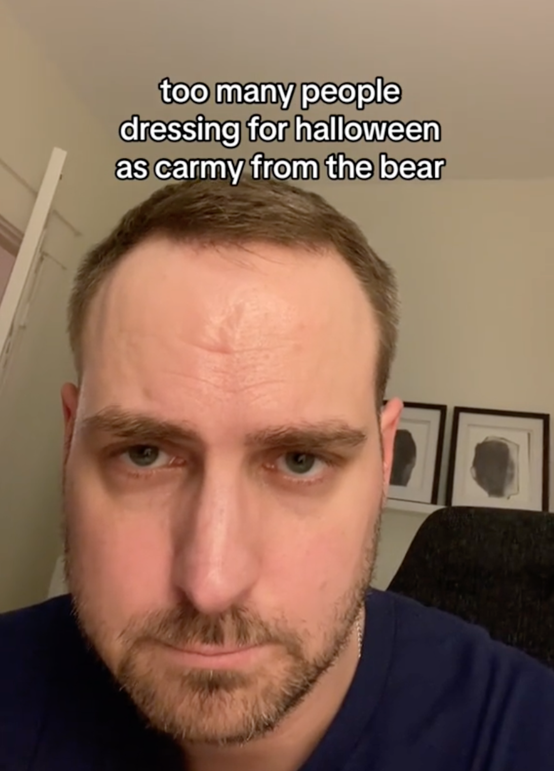 Young man with a beard looking at the camera looking serious.