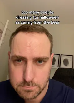 Young man with a beard looking at the camera looking serious.