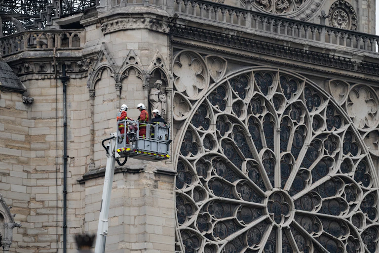Un grupo de bomberos elevados al lado del rosetón de Notre Dame.