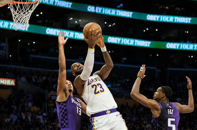 Un homme tient un ballon de basketball et tente de marquer un point.