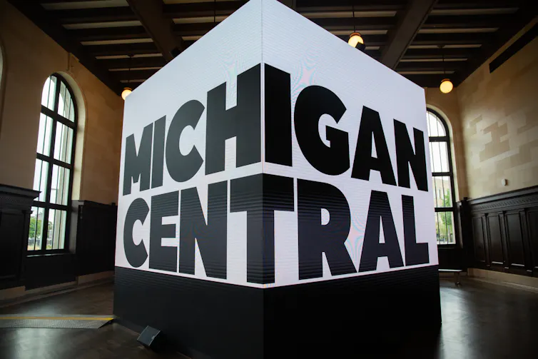 A huge screen inside a historic structure reads 'MICHIGAN CENTRAL'