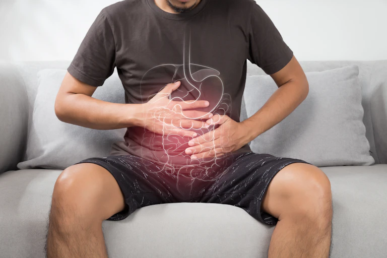 A man clutching his gut, with illustration of digestive system superimposed on him