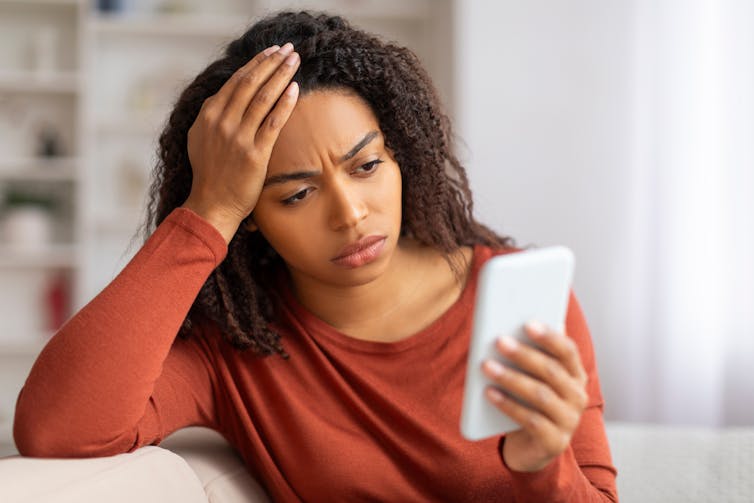A woman looking at her phone, looking frustrated