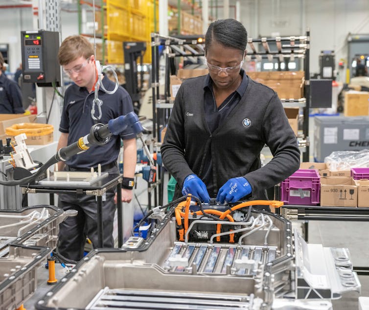 A woman works on battery assembly.
