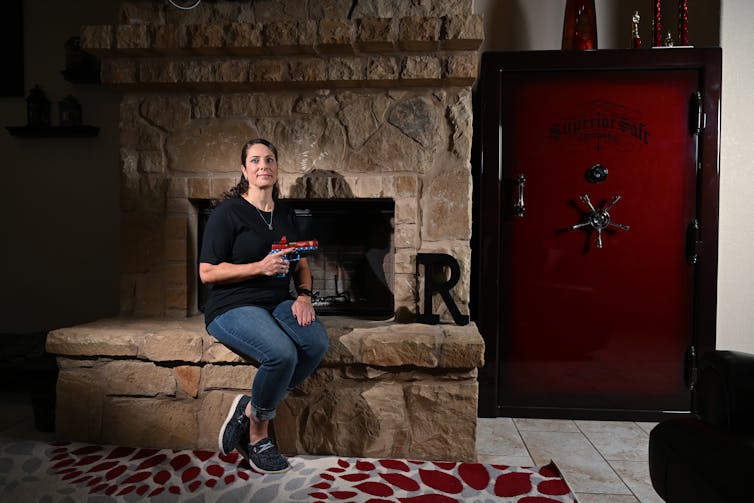 woman posing in front of fireplace holding her pistol