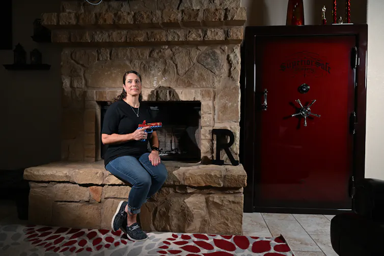 woman posing in front of fireplace holding her pistol