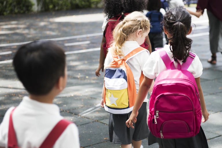 Children in uniform approach school.