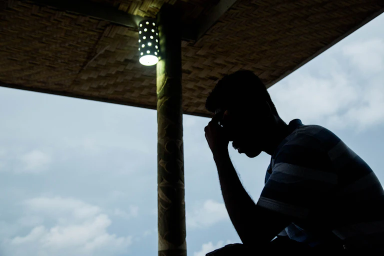 The silhouette of a man holding his head with his hand
